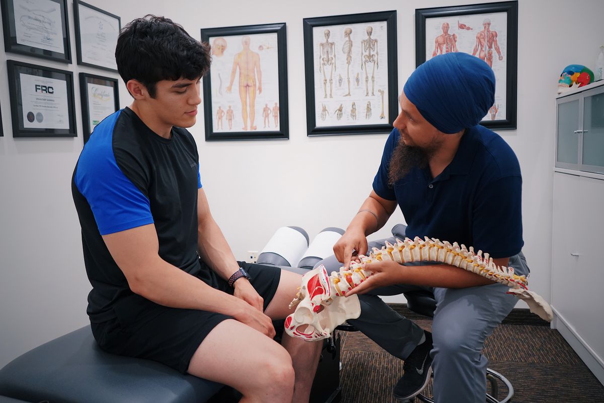 Doctor explaining a herniated disc to a patient using a spine model at Iron Spine Medical in Lakeland, Florida